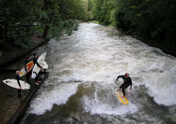 Surfers on the Eisbach branch of the Isar River, as seen from the Eisbach Bridge, Englisher Garten, Munich, Germany