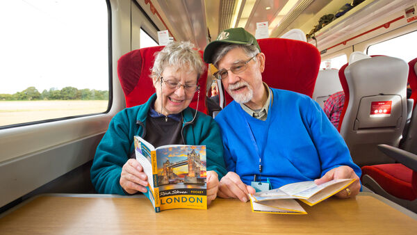 Tour members reading their Pocket London guidebook on the train, England