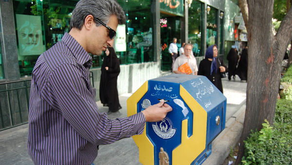 Man making a donation to a religious offering box, Iran