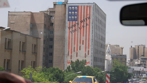 A mural of an sideways American flag on the side of a building that says "Down with the USA", Iran