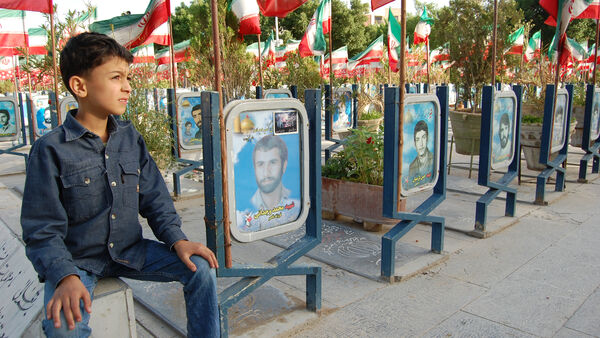 A boy sitting near the graves, Iran