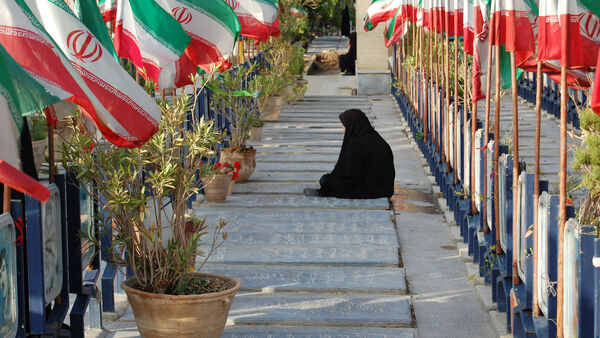 A mother rests near graves, Iran