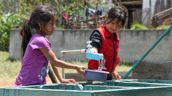 Girls pouring water from a tap, Guatemala