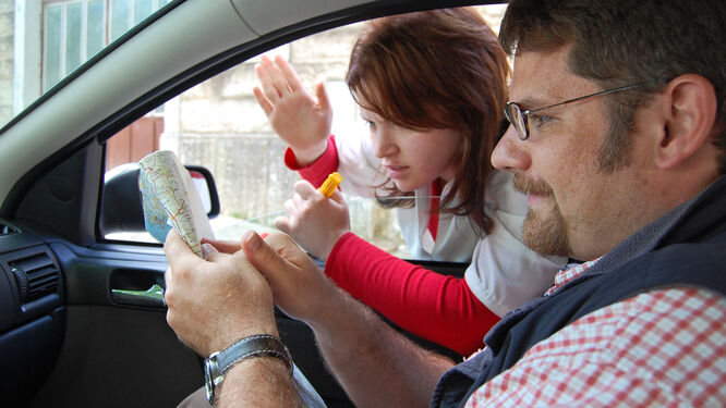 Man in car and woman looking at a map