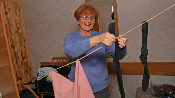 Woman hanging up laundry on a clothesline in hotel room