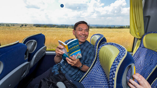 Man reading a guidebook on a bus