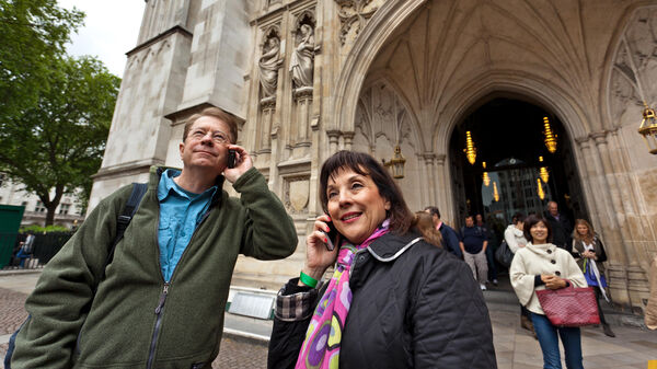 Couple using cell phones outside Westminster Abbey, London, England