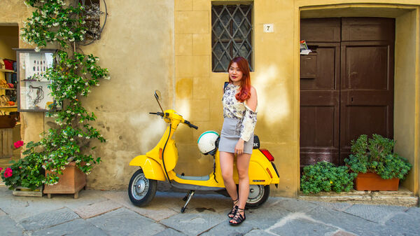 Vespa parked with driver, Pienza, Italy