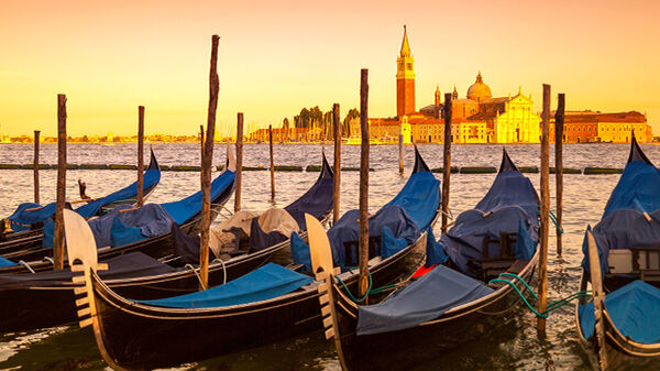 Venetian gondolas bobbing near St. Mark's Square at sunset, with the island of San Giorgio Maggiore in the background