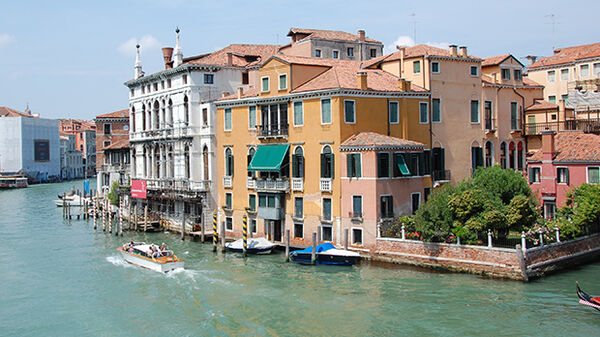 Colorful buildings on Venice's Grand Canal, with the white Baroque Palazzo Giustinian Lolin