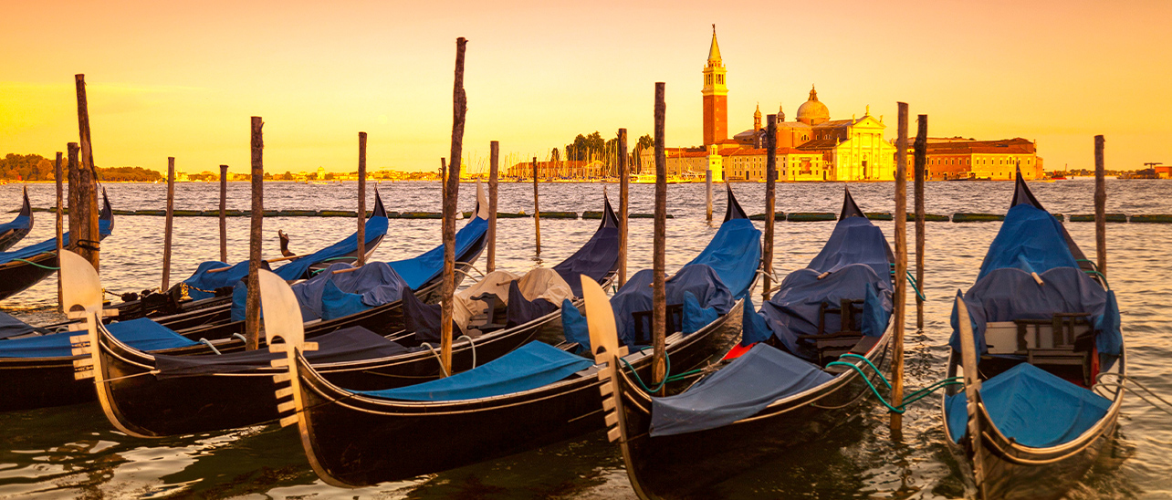 Venetian gondolas bobbing near St. Mark's Square at sunset, with the island of San Giorgio Maggiore in the background