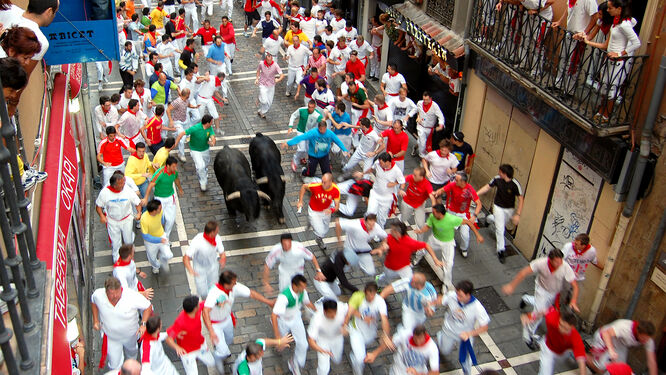 Surrounded by runners and spectators, bulls charge through the streets of Pamplona, Spain, during the Festival of San Fermín's Running of the Bulls
