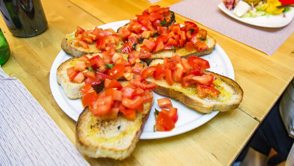 Six pieces of appetizing bruschetta on a paper plate and wooden table in Rome