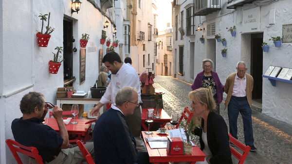 People eating and strolling the streets of Spain's Arcos de la Frontera