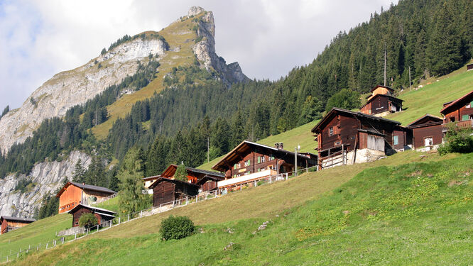 Wooden huts and chalets lining a road above the alpine Swiss village of Gimmelwald