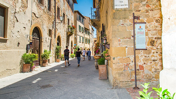 Shady street of stone buildings in Pienza, Italy