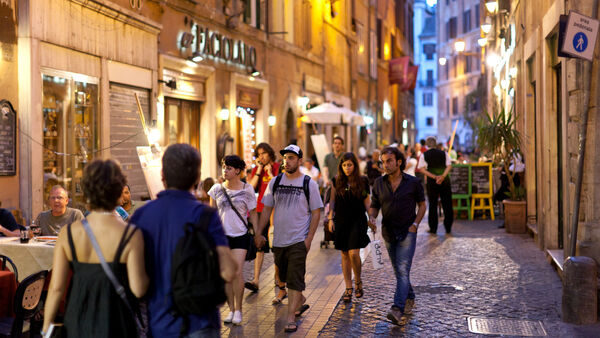 People strolling along a narrow street in Rome at evening