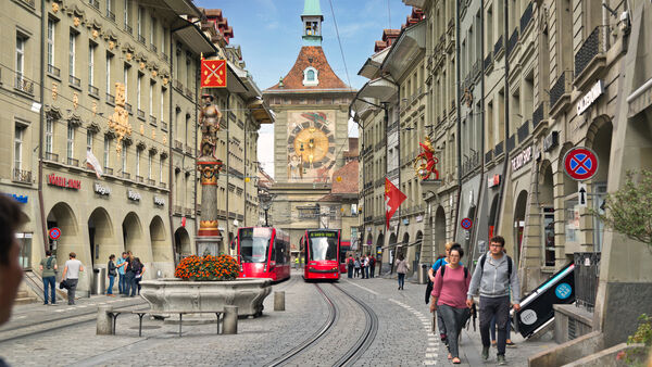 Bern's pedestrianized Marktgasse, with its colorful Schützenbrunnen fountain, electric trams, and the iconic Zytglogge clock tower