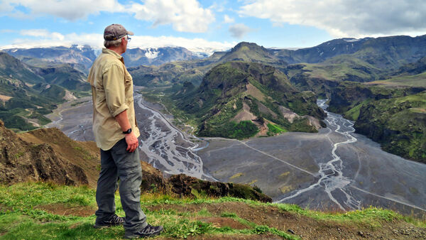 Man looking out across a river valley to the volcano of Katla from Valahnúkur, in Þórsmörk (Thor's Woods), Iceland