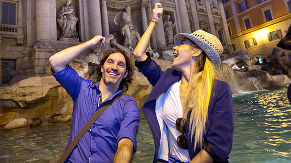Couple tossing coins into Trevi fountain, Rome