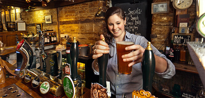 Lady bartender with beer pint in pub, London, England