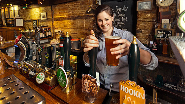 Lady bartender with beer pint in pub, London, England