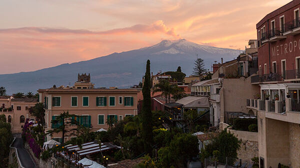 Mount Etna and rooftops at dusk, Sicily, Italy