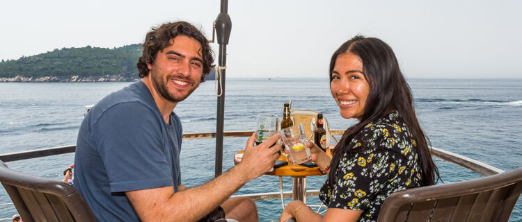 Young couple with drinks at sea overview, Croatia