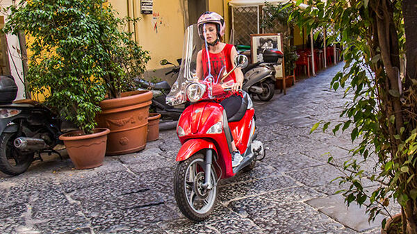 Lady riding red scooter, Naples, Italy
