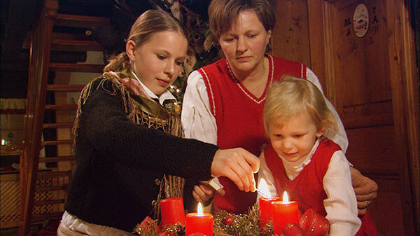 a mother and two daughters lighting an advent wreath