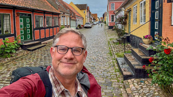 Cameron Hewitt on cobbled street with colorful houses, Aero, Denmark