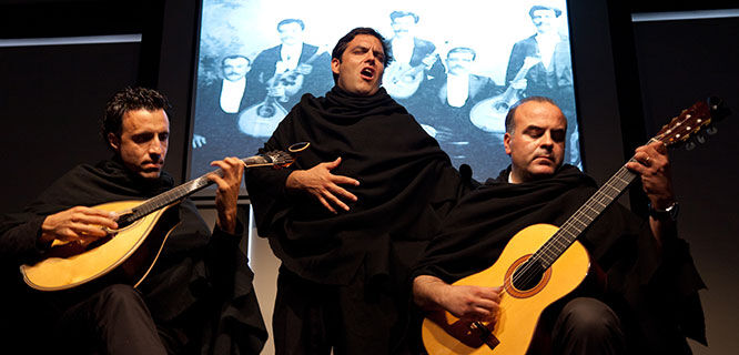 man singing fado with two guitarists