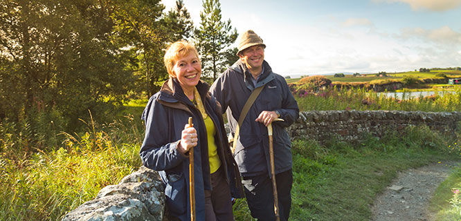 man and woman standing in fron to hadrians wall