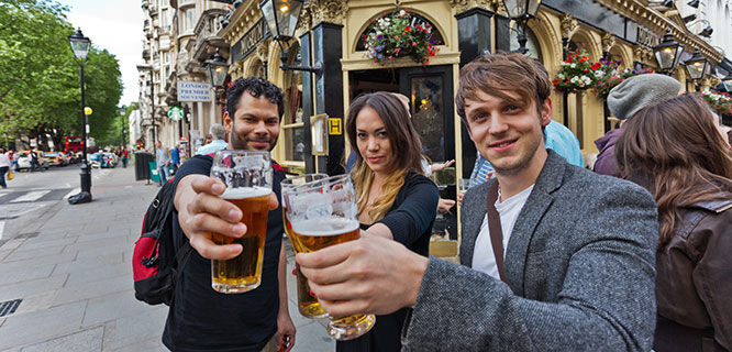 two men and a woman drinking beer at a pub in london
