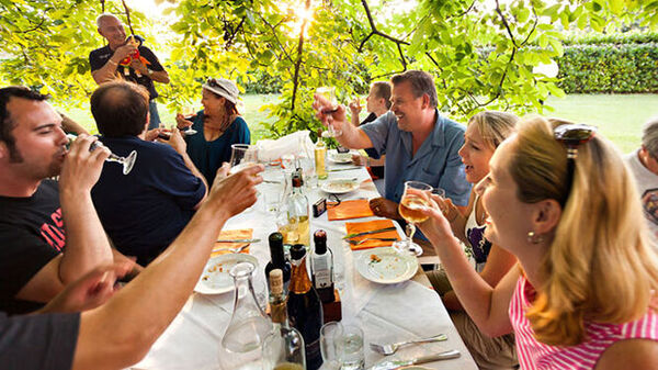 people eating dinner outside under green trees