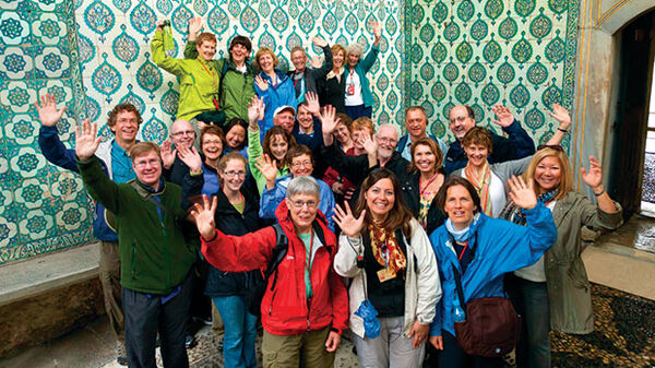 group of people standing in front of beautiful blue and green painted tiles