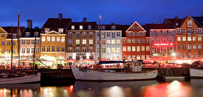 colorful buildings along copenhagen canal lit up at night