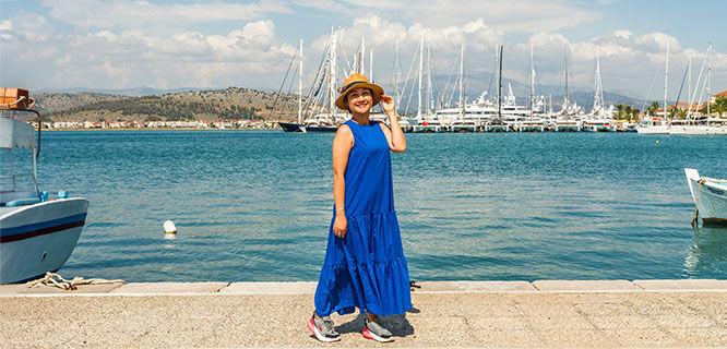 woman in blue dress walking along the harbor in nafplio