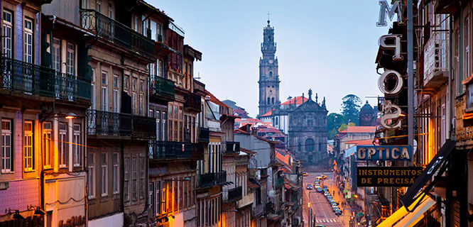a tower at the end of a narrow street at sunset