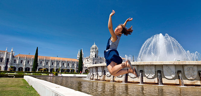 Girl jumping in front of fountain, Belem, Lisbon, Portugal