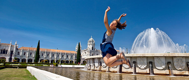 Girl jumping in front of fountain, Belem, Lisbon, Portugal