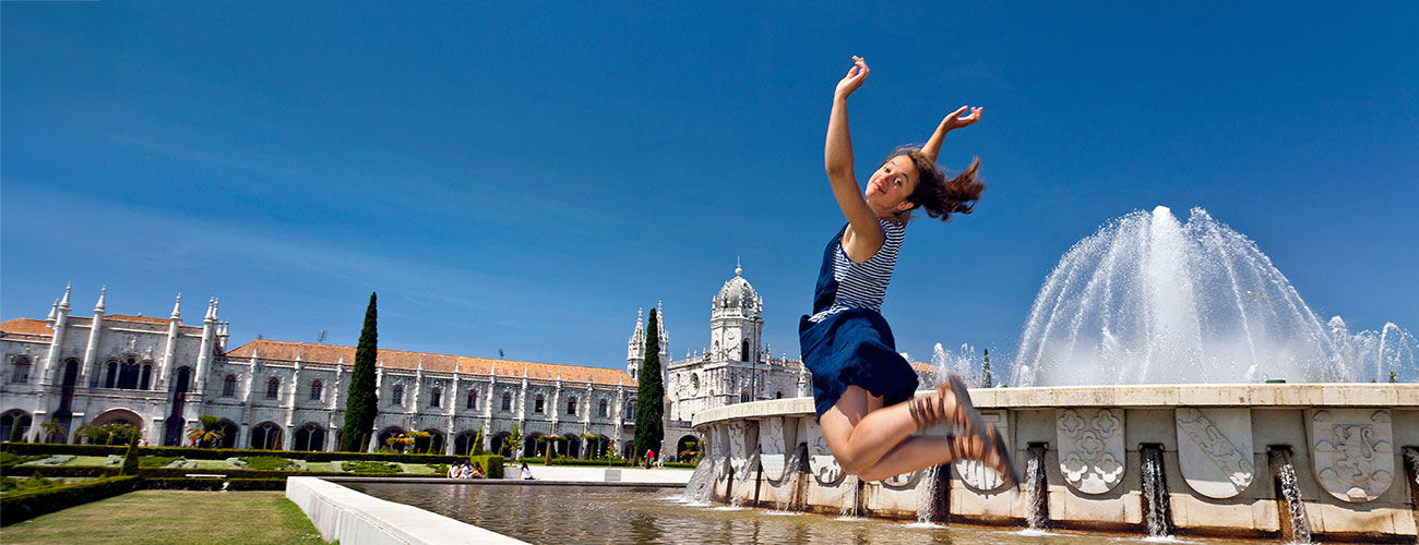 Girl jumping in front of fountain, Belem, Lisbon, Portugal