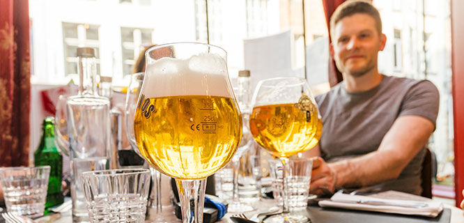 two belgian beer chalices with man in background