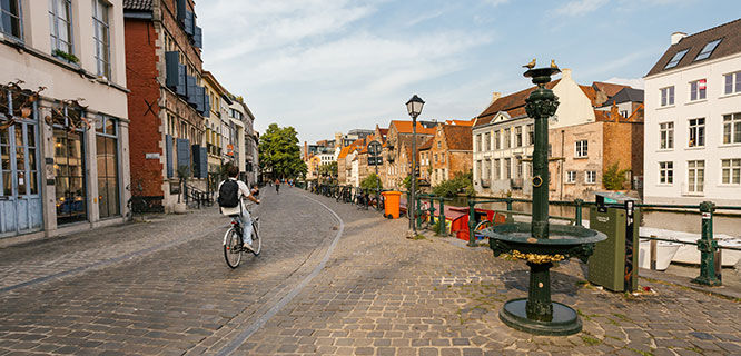 cobble stone street with bike riding along a canal