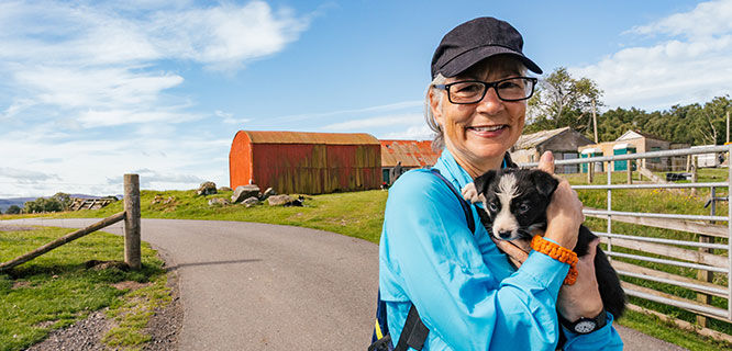 woman holding black and white puppy