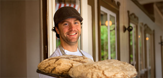 man-holding a tray with two loaves of bread