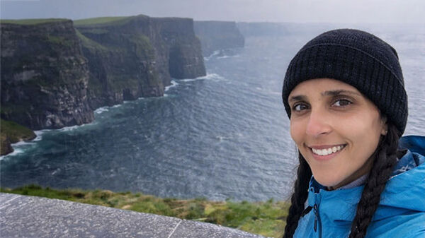 woman wearing knit cap with cliffs and water in background