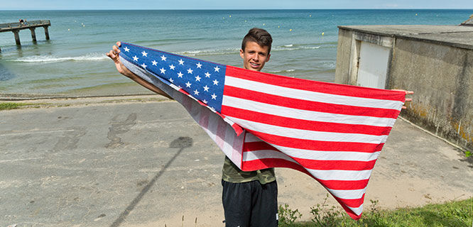 Boy with American flag on Omaha Beach, Normandy, France