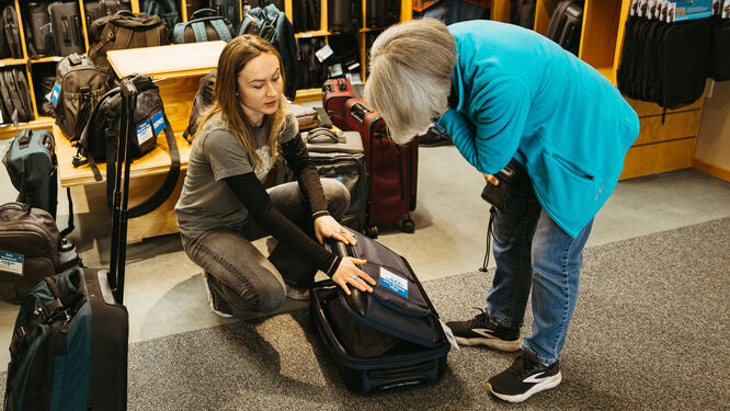a woman showing another woman the inside of a travel bag