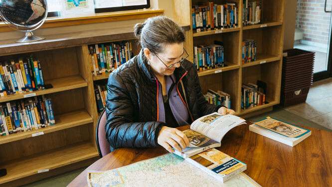 a woman sitting at a table in a library reading